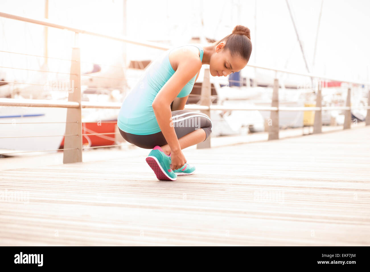 Young healthy girl tying her running shoe laces at sunrise Stock Photo
