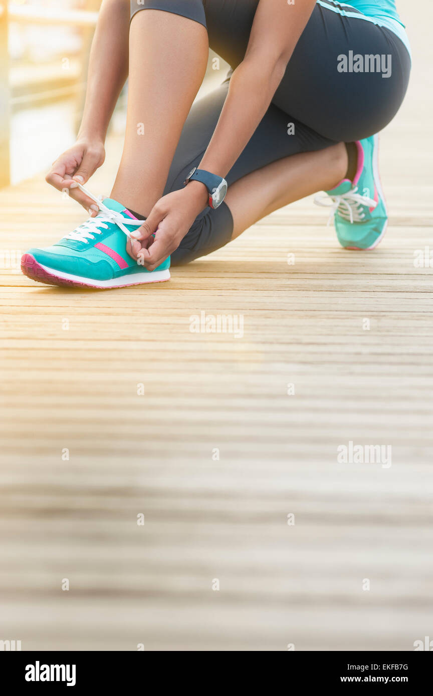 Young mixed race girl tying her running shoe laces Stock Photo