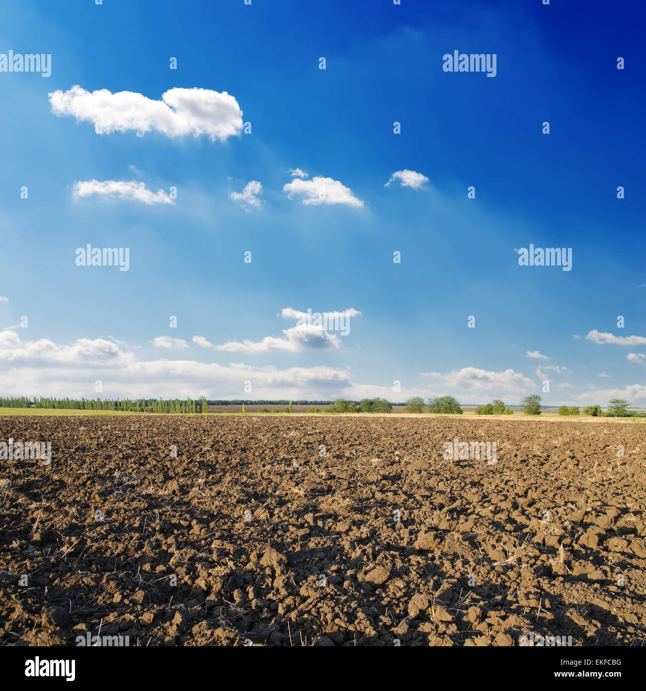 black ploughed field under deep blue sky with clouds Stock Photo - Alamy