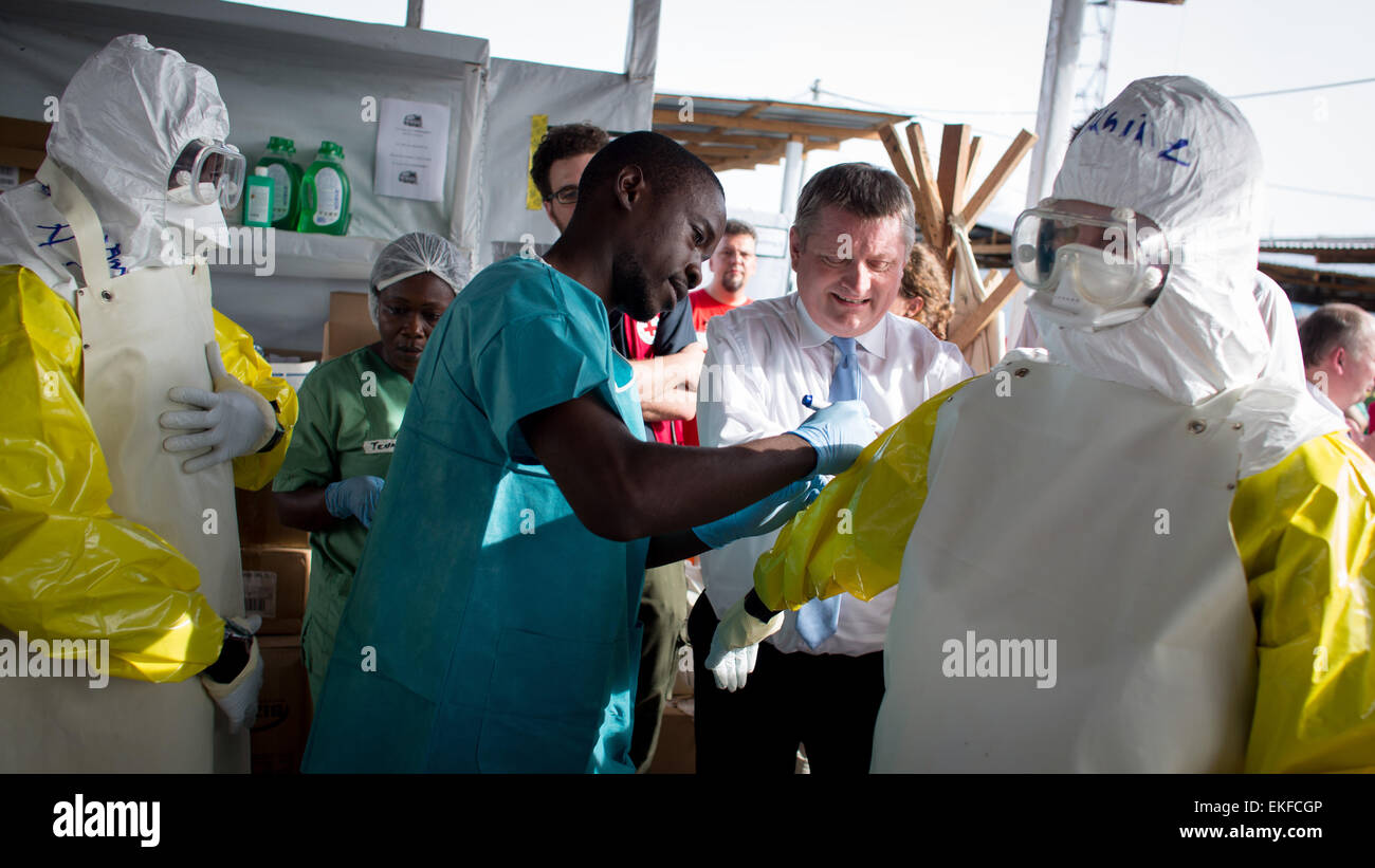 Monrovia, Liberia. 09th Apr, 2015. German Federal Minister of Health Hermann Groehe (C) writes on a worker's protective suit the time it was put on ' at the SITTU (Severe Infections Temporary Treatment Unit) in Monrovia, Liberia, 09 April 2015. German Federal Ministers Groehe and Mueller are traveling to Liberia and visiting the SITTU in order to discuss reconstruction after the Ebola epidemic. Photo: KAY NIETFELD/dpa/Alamy Live News Stock Photo