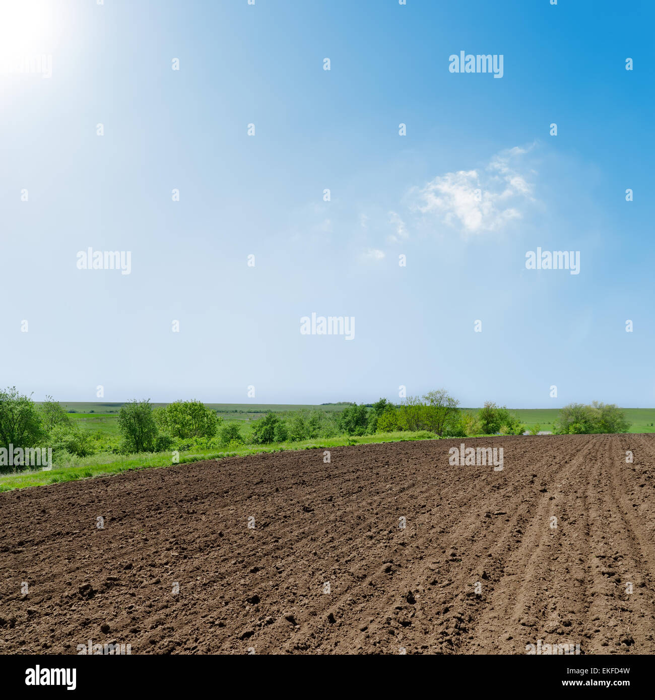 black ploughed field under deep blue sky with sun Stock Photo - Alamy