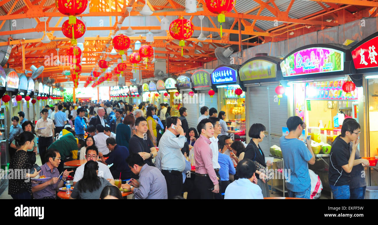 Locals eat at a popular food hall in Singapore. Inexpensive food stalls are numerous in the city so Stock Photo