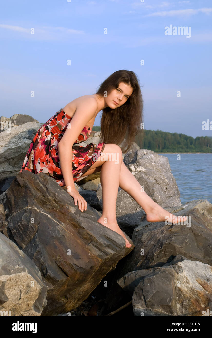 Beautiful girl sit on rock on sea coast Stock Photo - Alamy