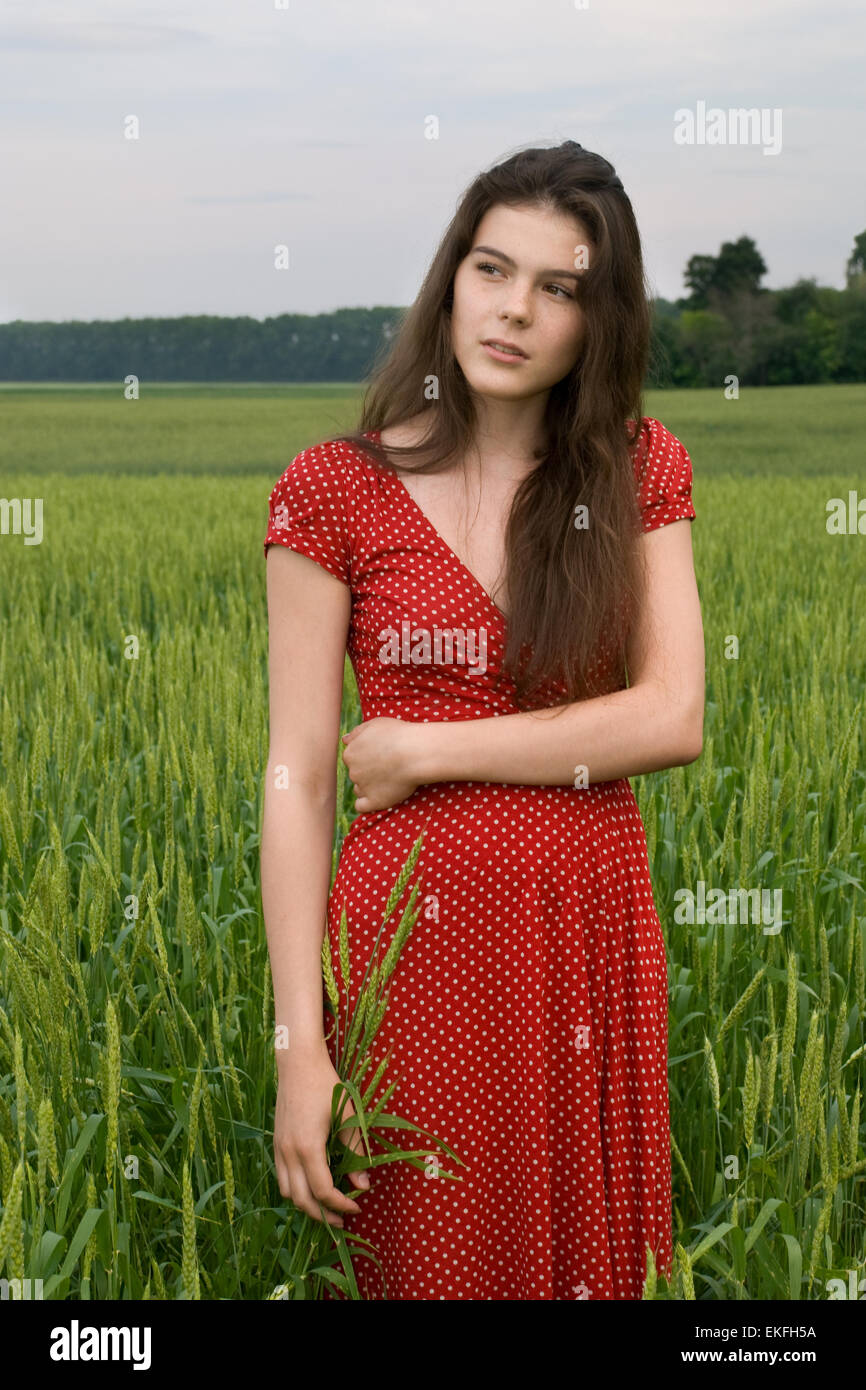 Beautiful girl weared red dress in green wheat field Stock Photo - Alamy