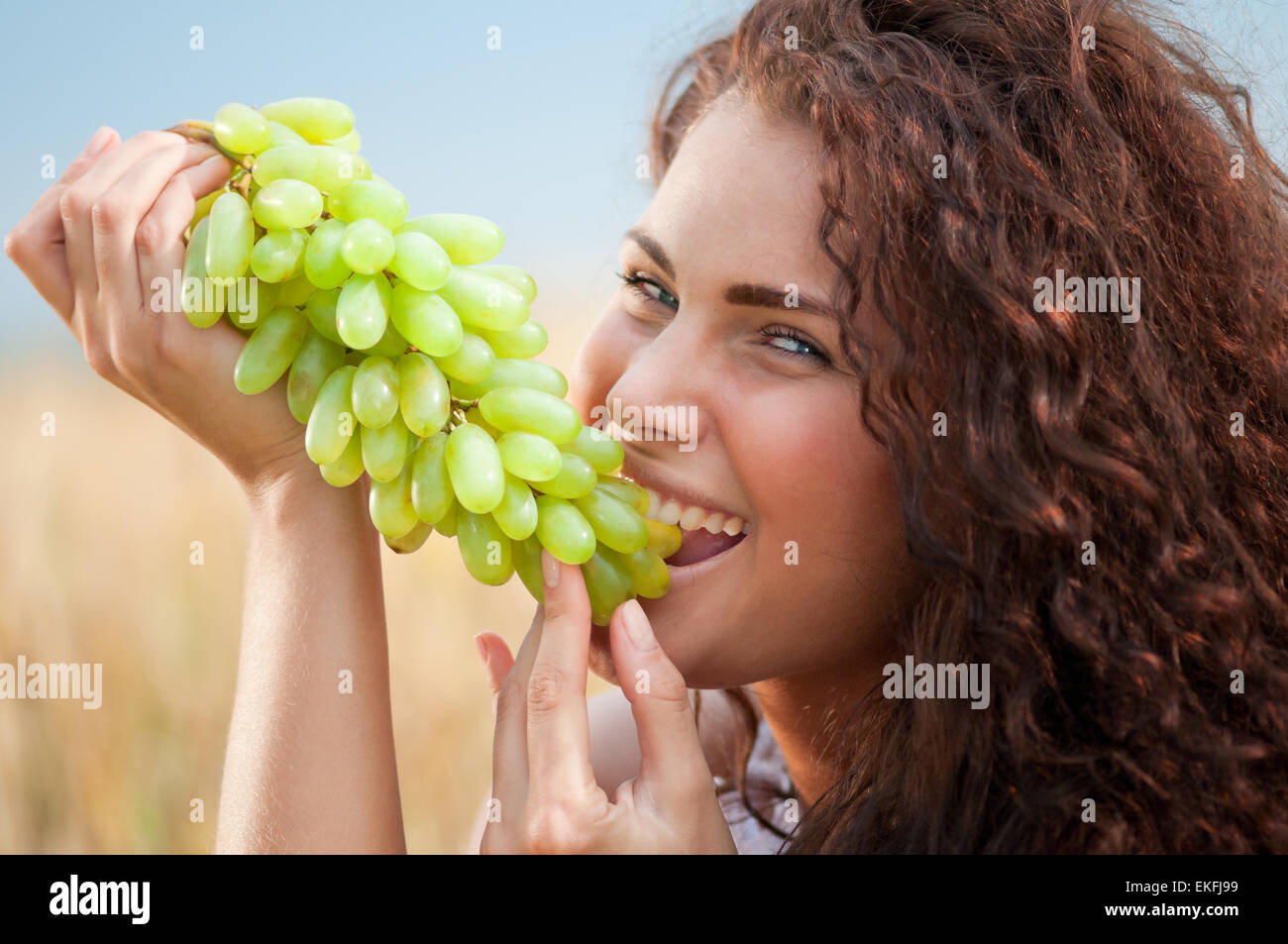 perfect woman eating grapes in wheat field. Picnic Stock Photo - Alamy