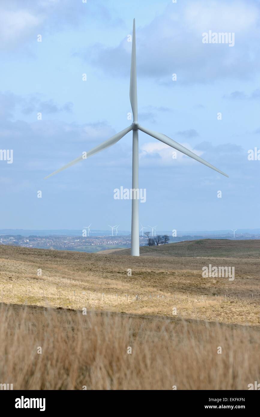 A wind driven turbine at a wind farm in Scotland, UK with the city of Glasgow behind it. Stock Photo