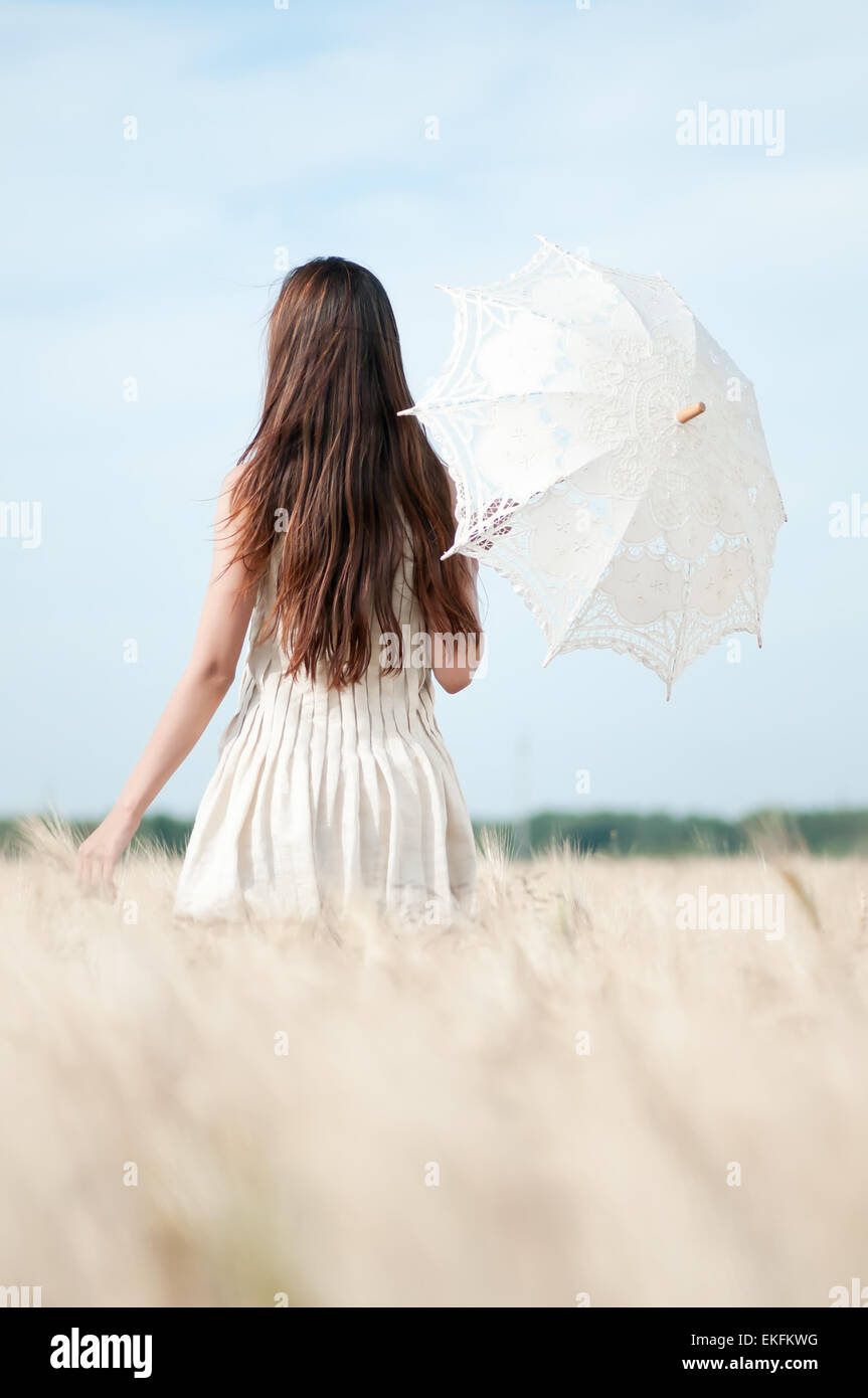 Woman with umbrella walking in field Stock Photo - Alamy
