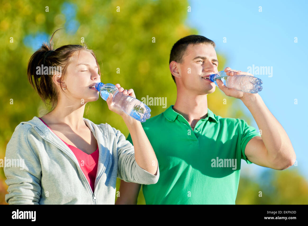 Teen boy wiping his brow and drinking water from a bottle, Stock image