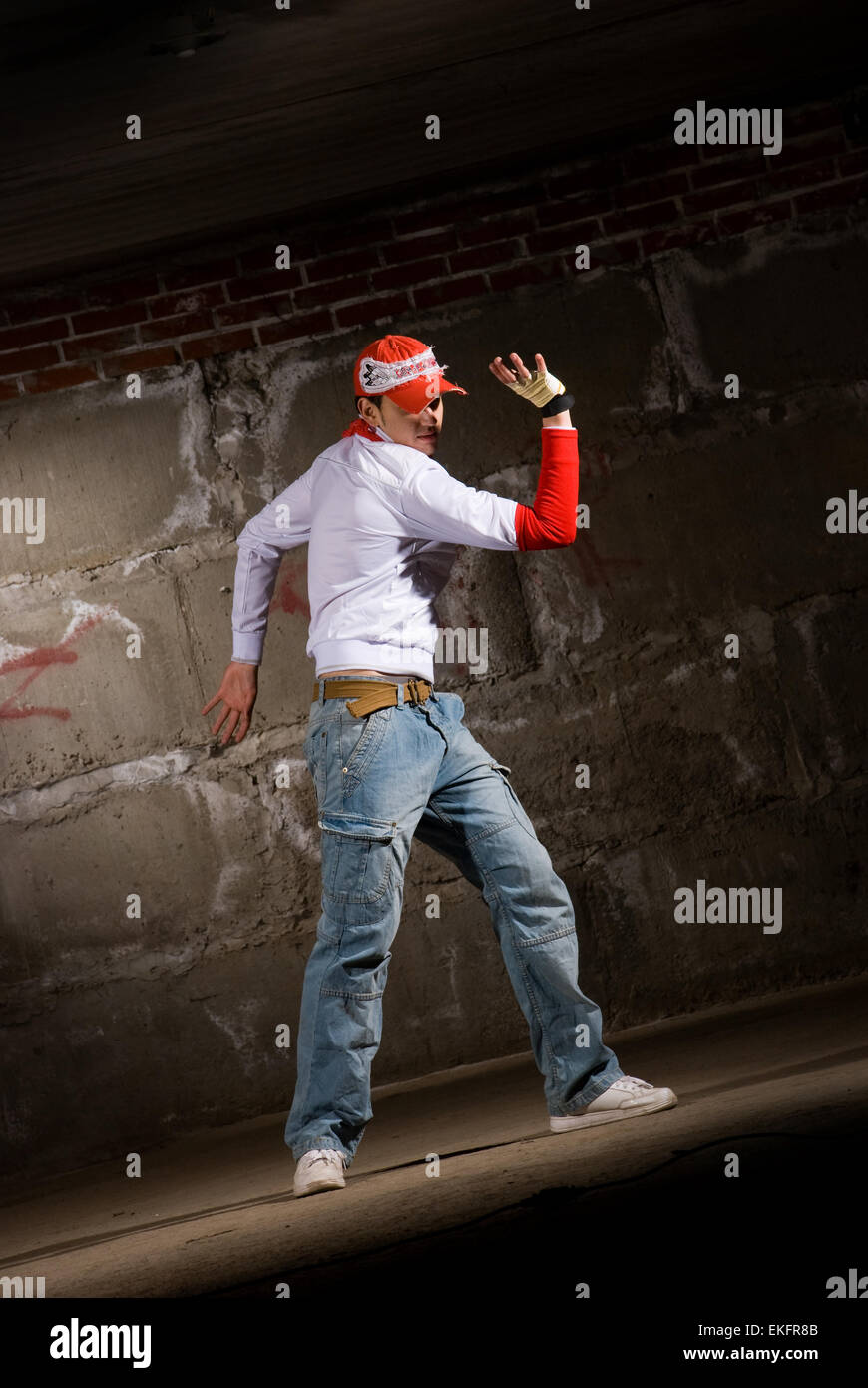 Hip hop boy dancing in modern style over grey brick wall Stock Photo