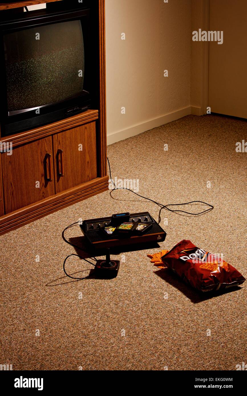 Vintage Atari video game console with a tv and bag of chips on the floor Stock Photo