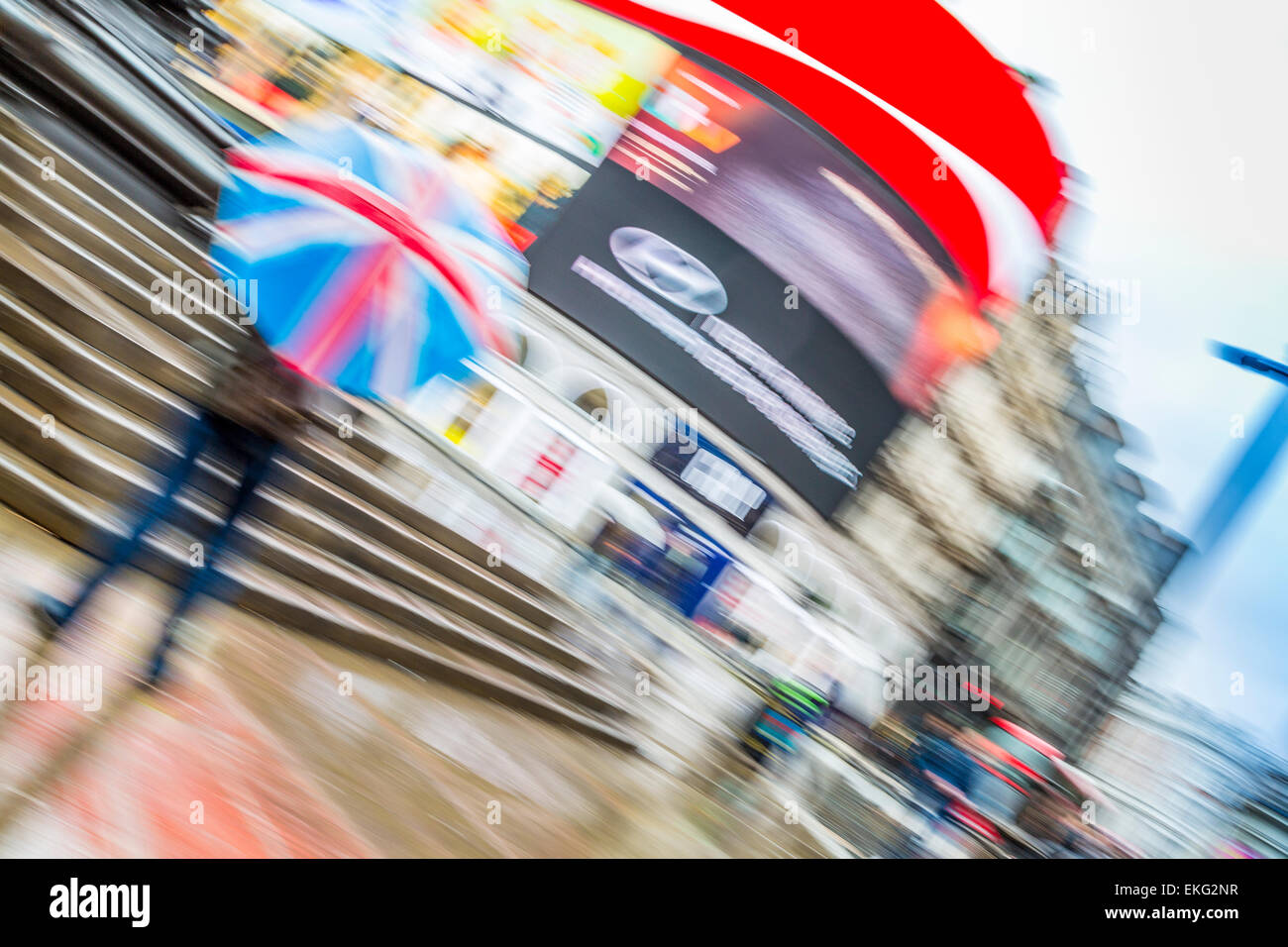 Piccadilly Circus concept blurred image with a man holding a Union Jack or Union flag umbrella in the rain , London England UK Stock Photo