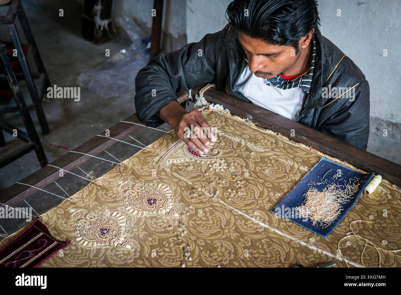 Craftsman hand embroidering fabric with gems and sequins in a textile factory in Jaipur, Rajasthan, India Stock Photo