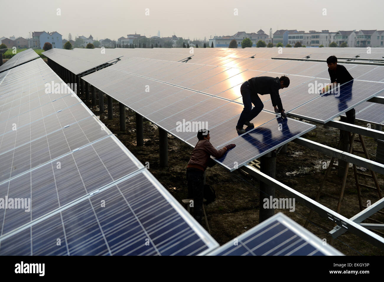 Jiaxing, China. 10th Apr, 2015. Tow workers work at a solar power generating plant which also will be used to be fish-farming underneath in Jiaxing, Hubei province China on 10th April 2015.China raised its solar target for 2015, promising to add almost 2 1/2 times as much capacity as the U.S. added last year, as it races to clear its increasingly polluted air.The world’s biggest emitter of carbon aims to install as much as 17.8 gigawatts of solar projects in 2015, the National Energy Administration said in March. Credit:  Panda Eye/Alamy Live News Stock Photo