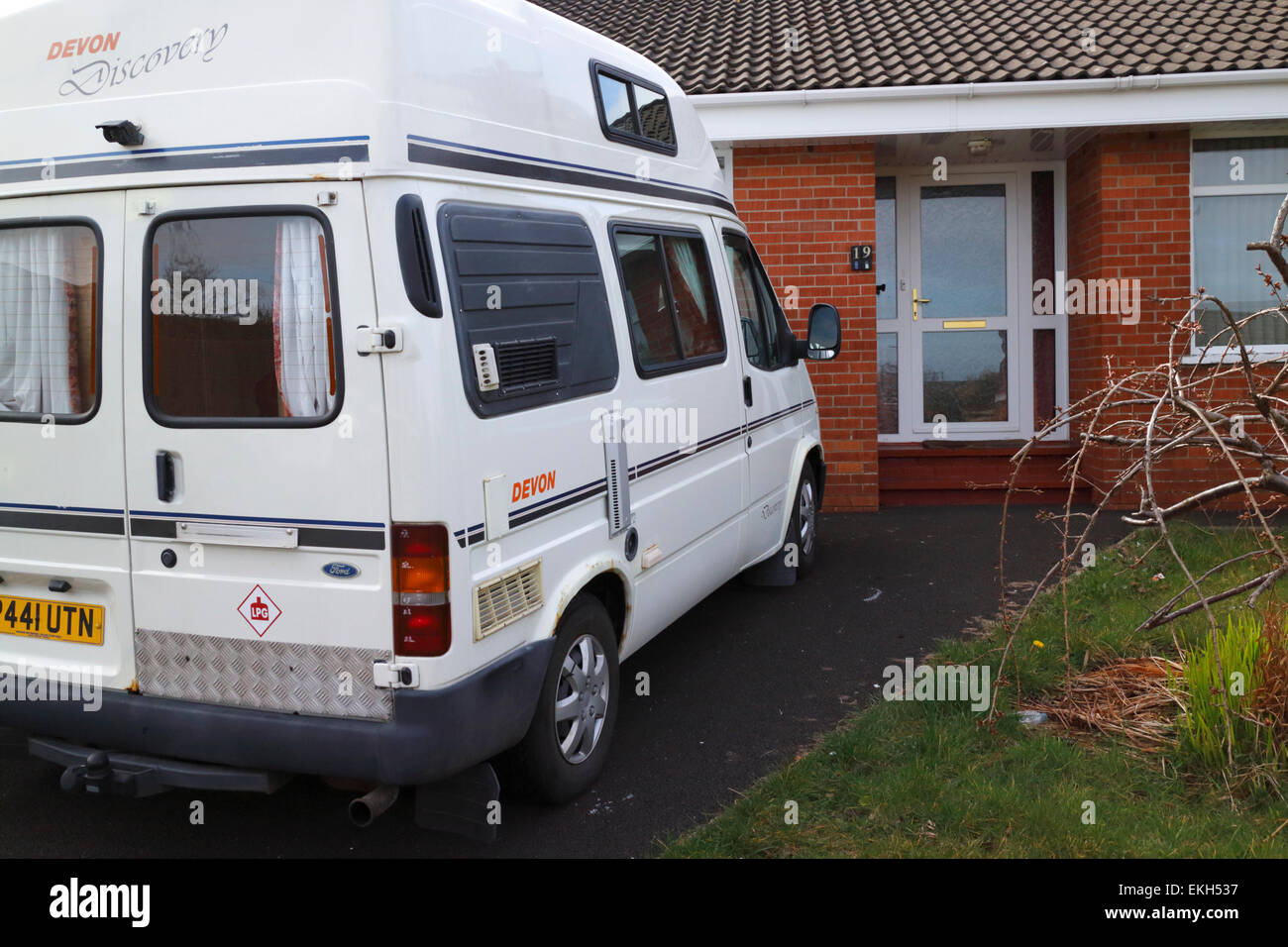 campervan parked in the driveway of a suburban house in the uk Stock Photo