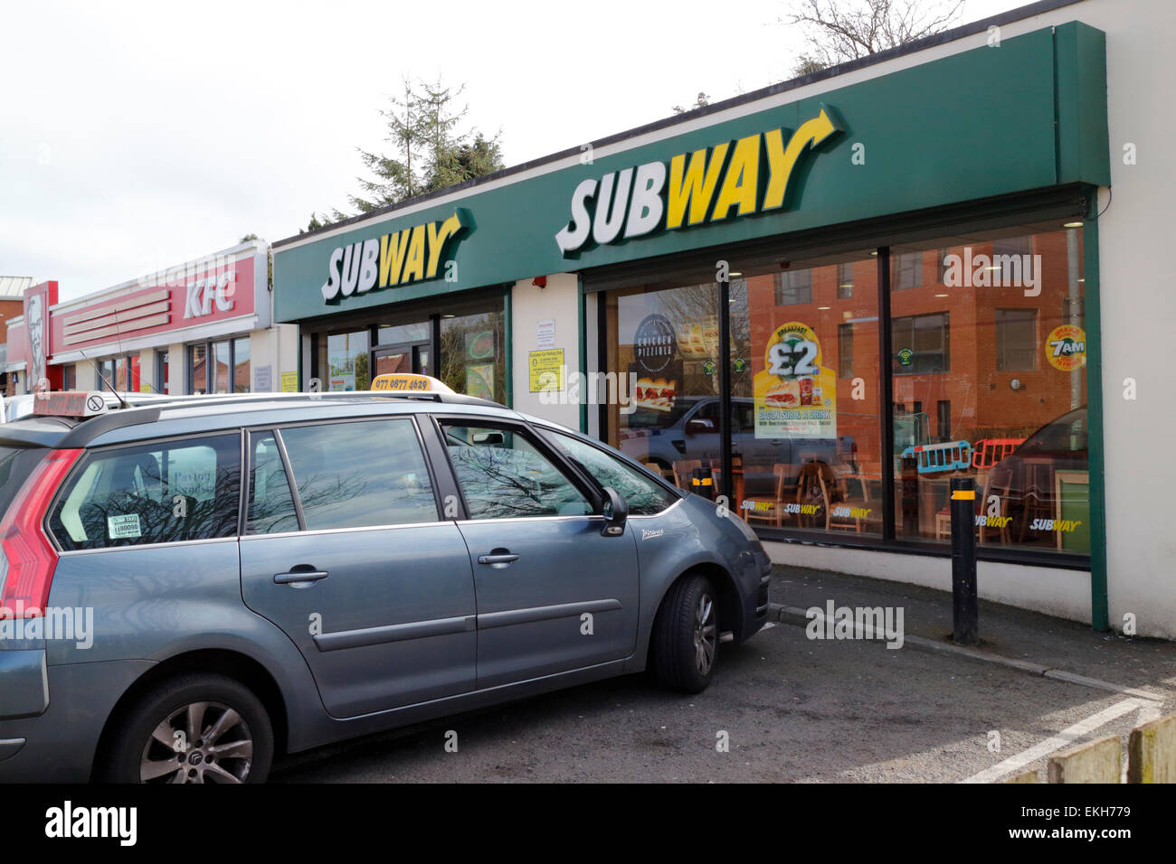 cars parked outside a busy subway and kfc restaurant in the uk Stock Photo