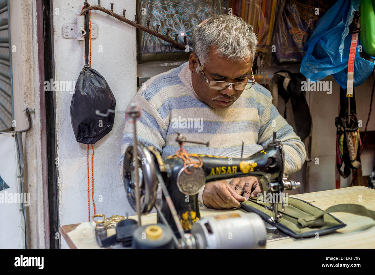 Unidentified Nepali tailor man sewing with old machine in a