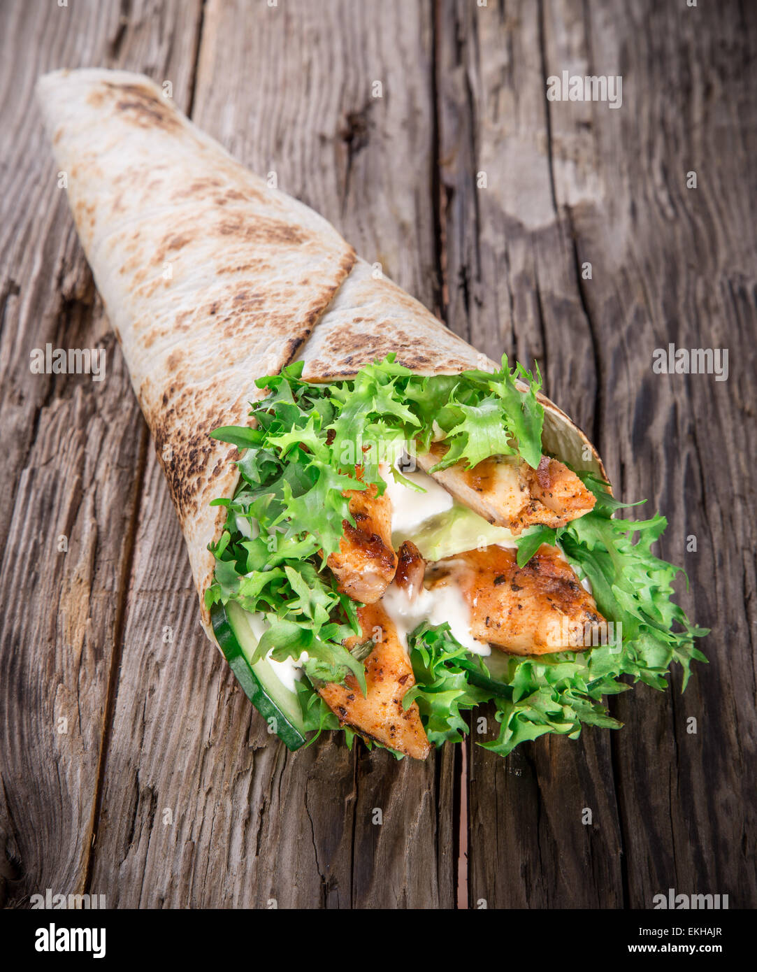 Chicken slices in a Tortilla Wrap with Lettuce on wood. Stock Photo