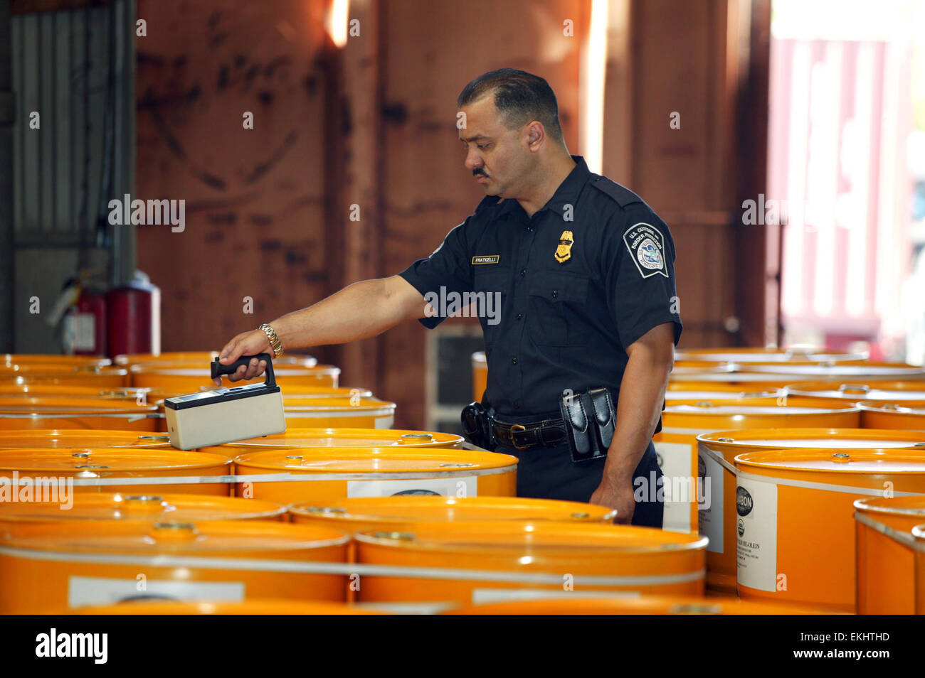 U.S. Customs and Border Patrol agent conducts search on barrel containers with the use of an electronic device called a Buster which shows space anomalies inside.  .  James Tourtellotte Stock Photo