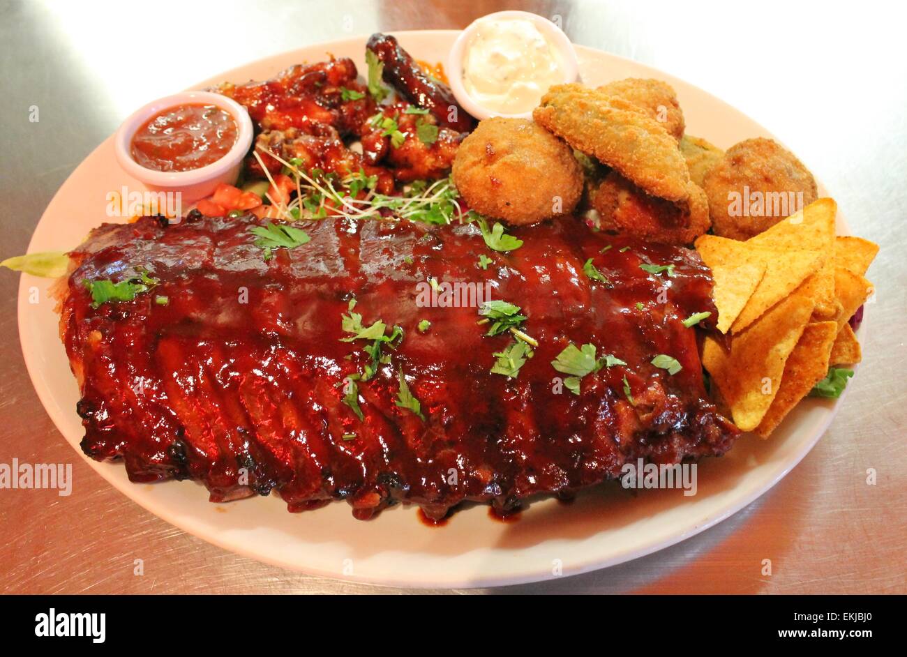 Tex mex BBQ baby back ribs and wings platter with nachos Stock Photo