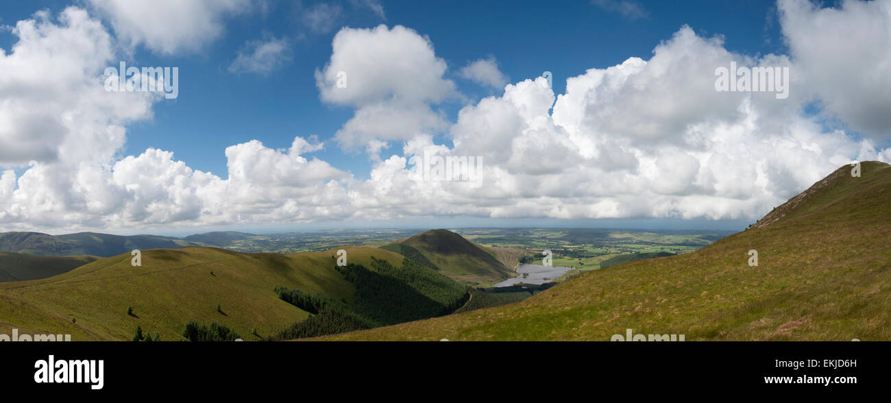 A panoramic shot looking West from Blake fell in Cumbria, England. The sky is blue with white puffy clouds. Stock Photo