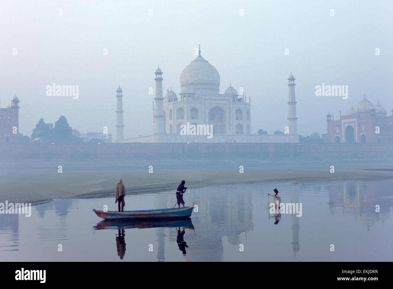 Man fishing next to a ferry boat in the Yamuna River, with the Taj Mahal behind, Agra, Uttar Pradesh, India Stock Photo