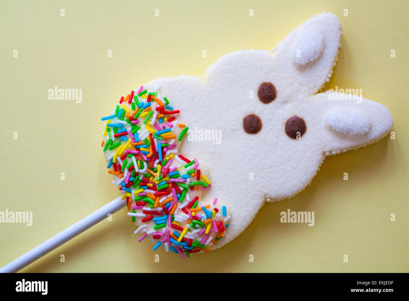 Easter Bunny marshmallow lollipop on pale yellow background Stock Photo