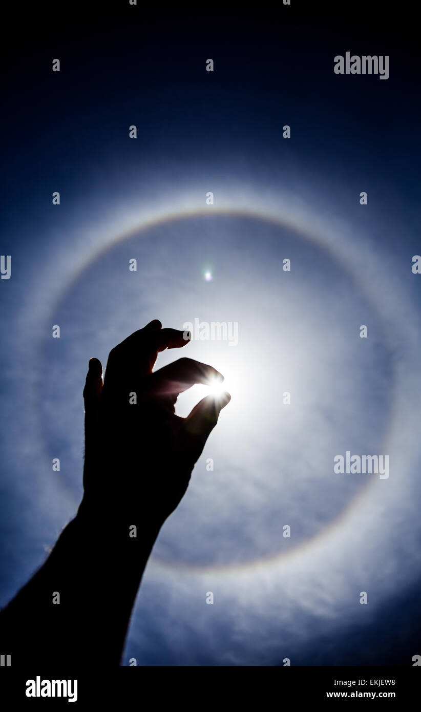 Hand silhouette with Circular Sun Halo in Background Stock Photo