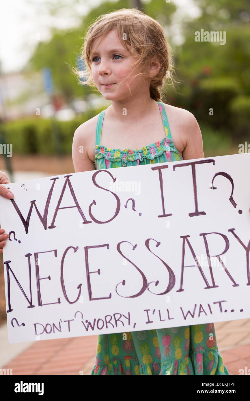 A young girl holds a sign during a vigil outside the North Charleston City Hall during a rally following the shooting death of Walter Scott April 10, 2015 in Charleston, South Carolina. Scott was shot multiple times by police after running from a traffic stop. Stock Photo