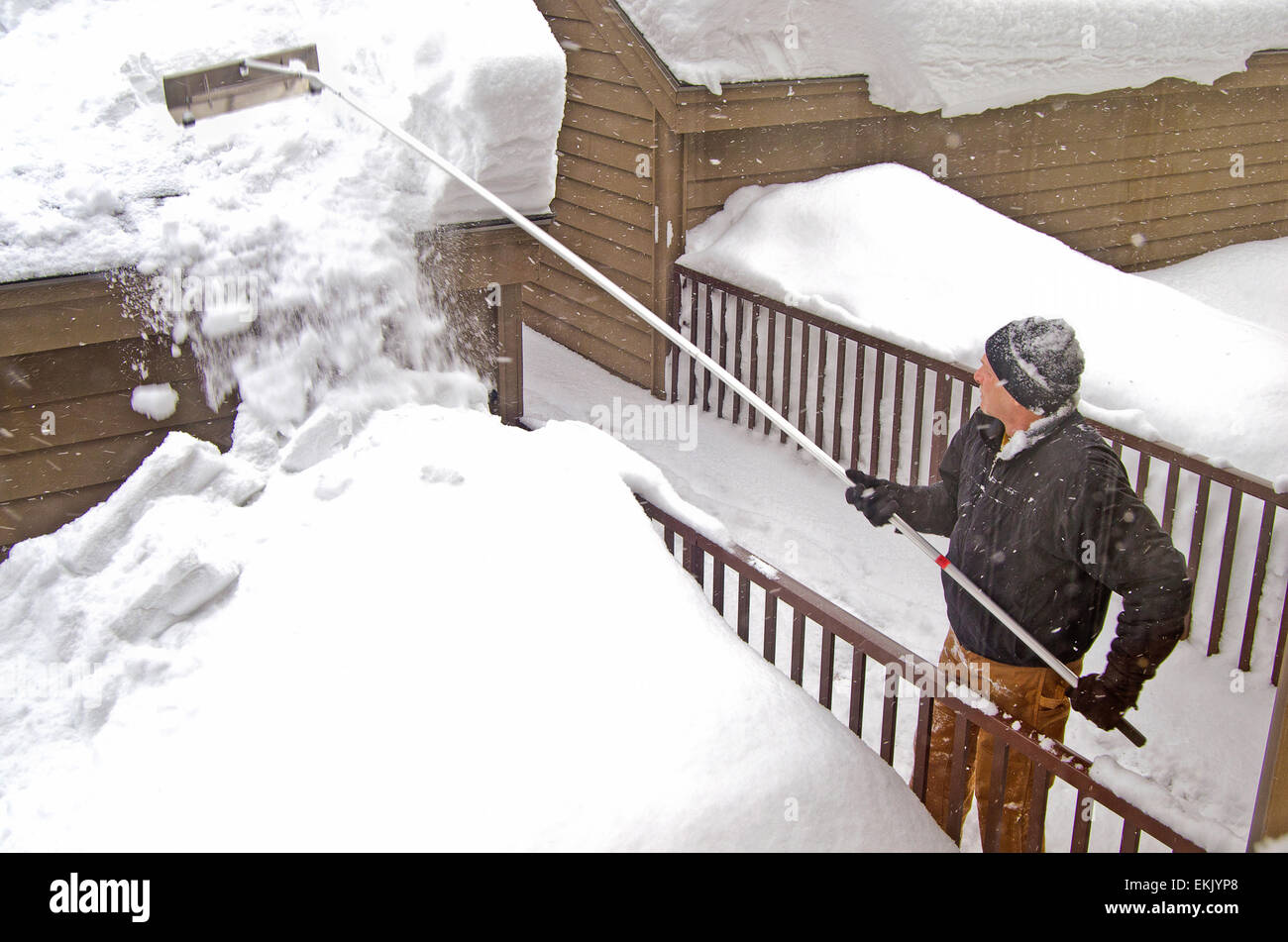 Man cleaning snow off garage roof with snow rake Stock Photo Alamy