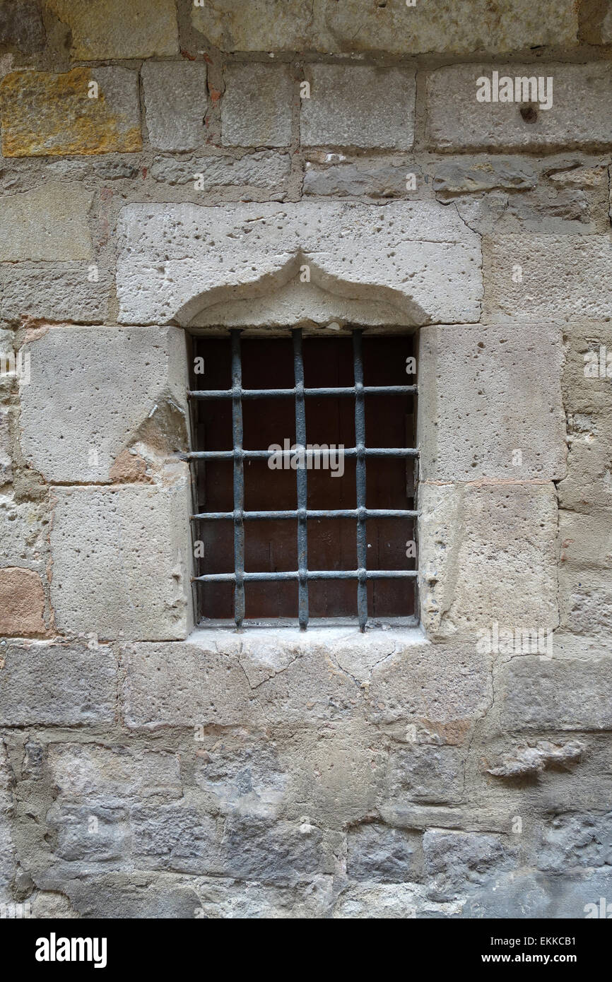 Window with metal bars in old stone wall in the Gothic Quarter of