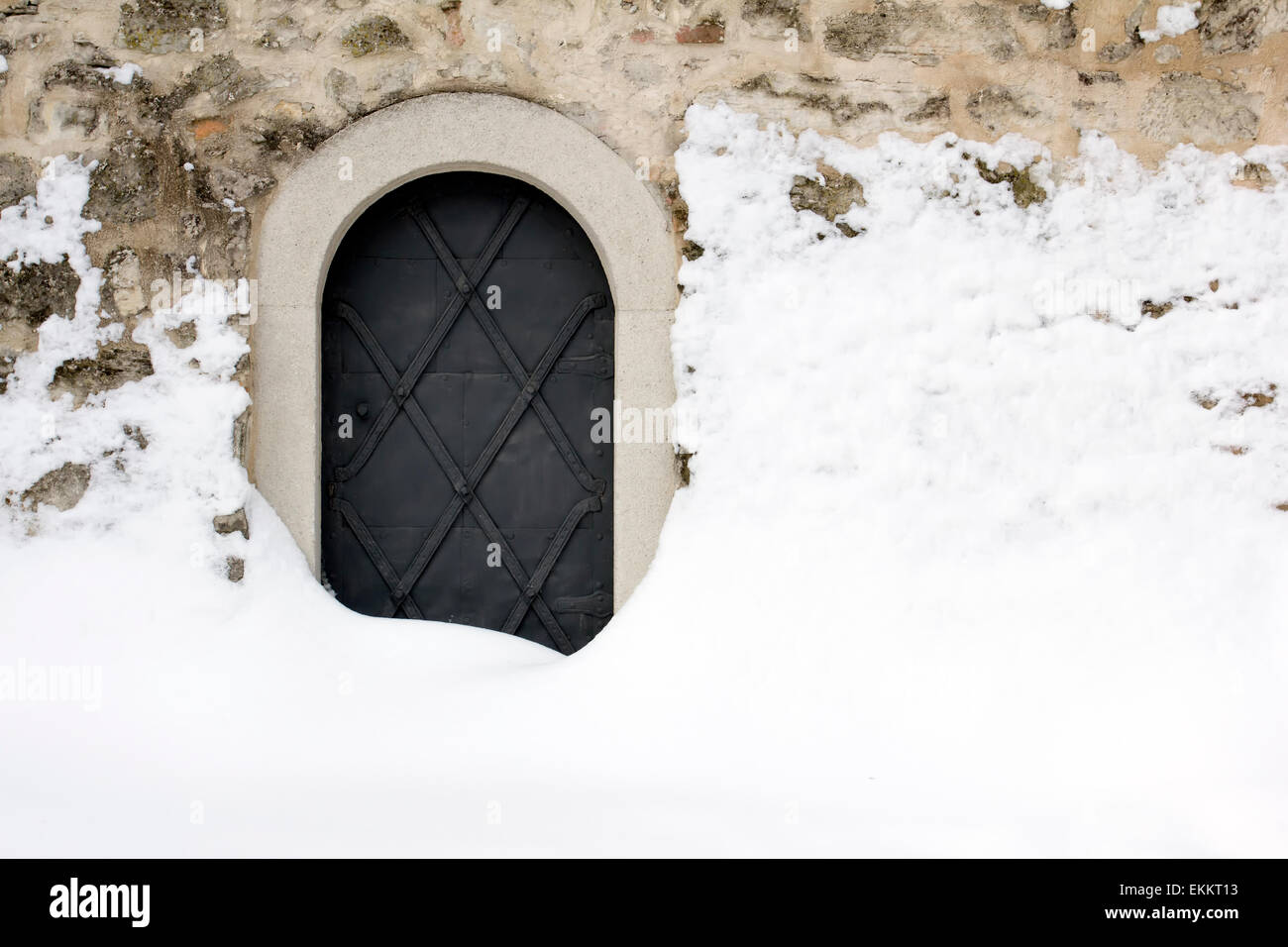 Small black iron castle door, backdoor, covered with snow. Stock Photo