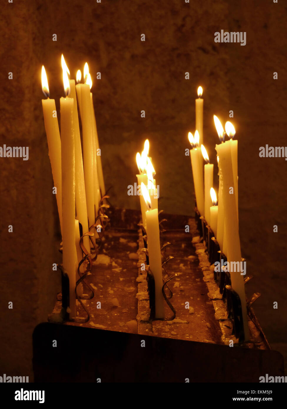 A candle holder in a church with lighted candles Stock Photo