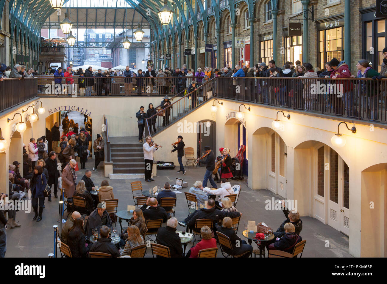 Crowds of tourists and shoppers listen to live music from a group of buskers in the South Hall of Covent Garden, London Stock Photo