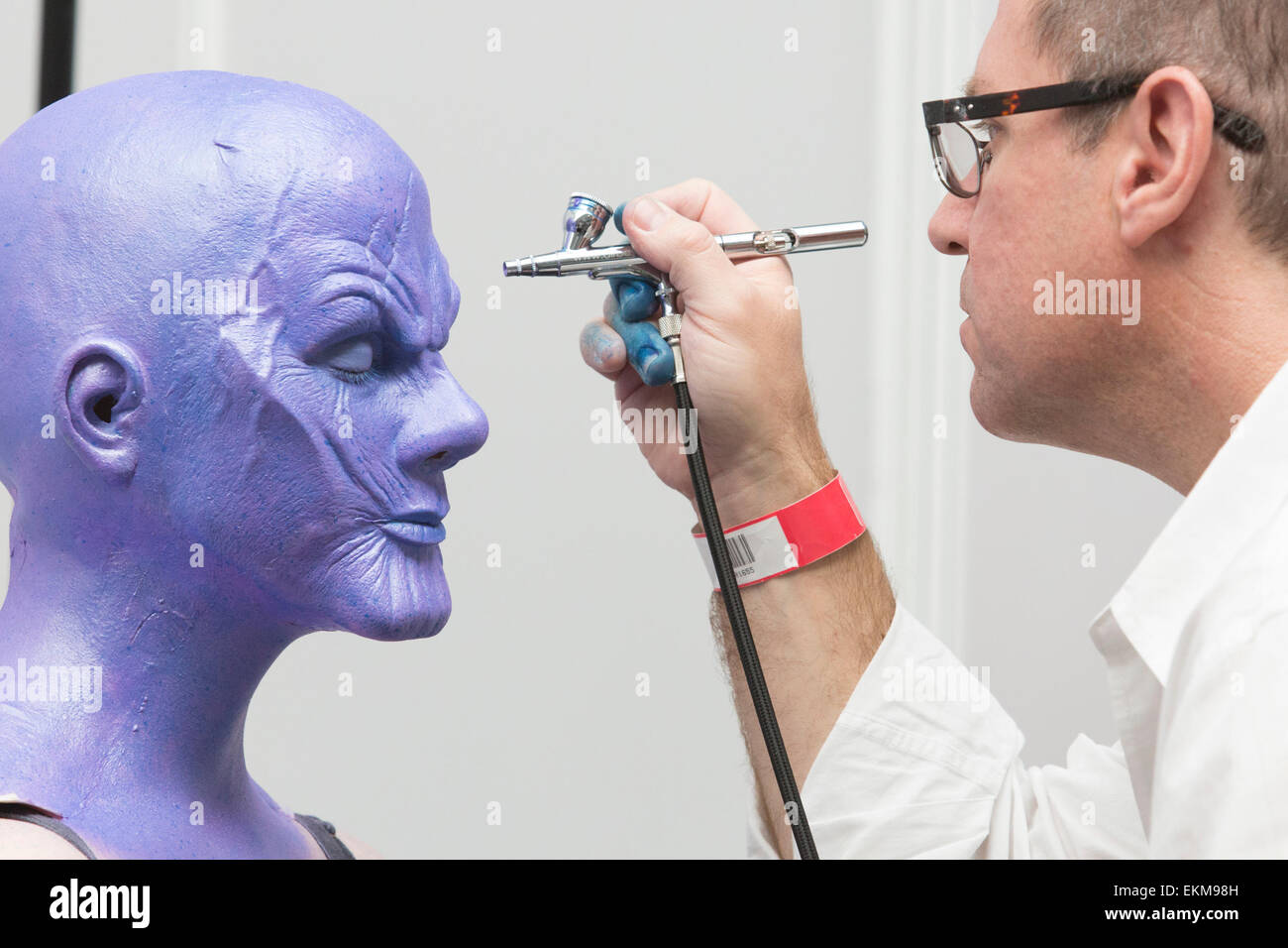 London, UK. 12 April 2015. Makeup Artist Chad Washam from Make-up designory  airbrushes makeup to a female version of the Avengers' villain Thanos.  United Makeup Artists Expo (UMAe), the UK's leading aspiring