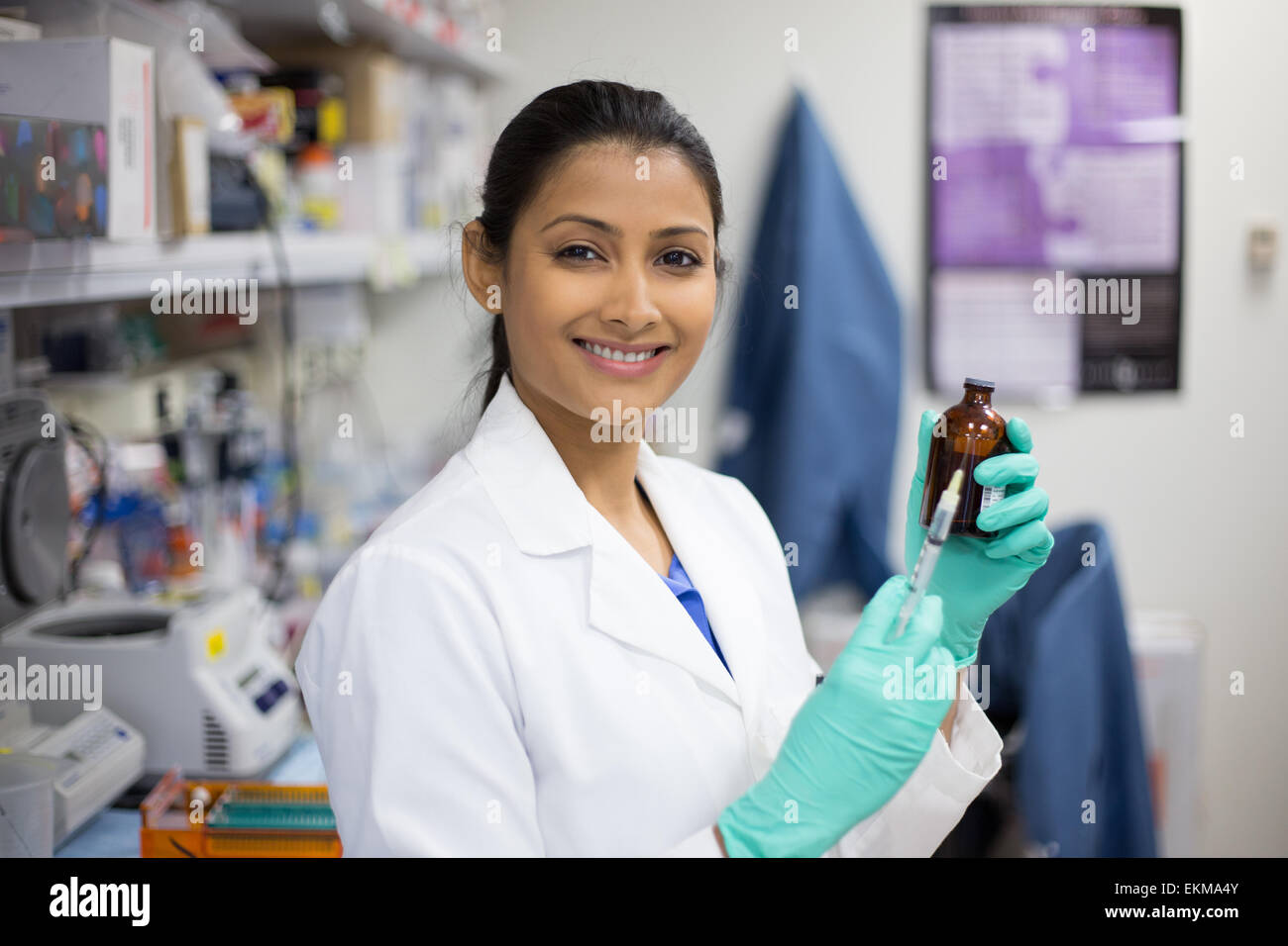 Closeup portrait, smart woman scientist in white labcoat holding syringe needle and brown bottle in isolated lab background Stock Photo