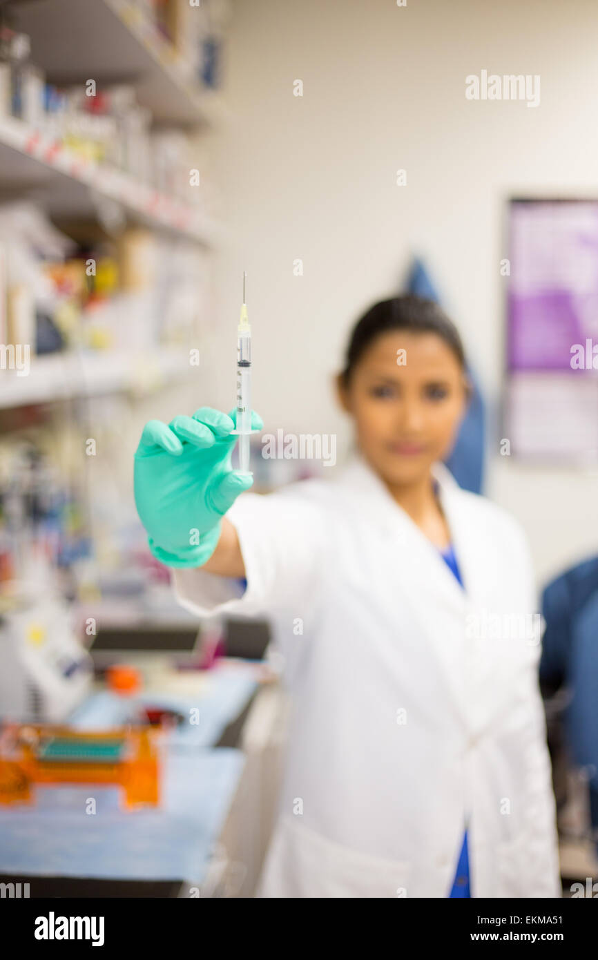 Closeup portrait, smart woman scientist in white labcoat showing close distance syringe needle, isolated lab background Stock Photo