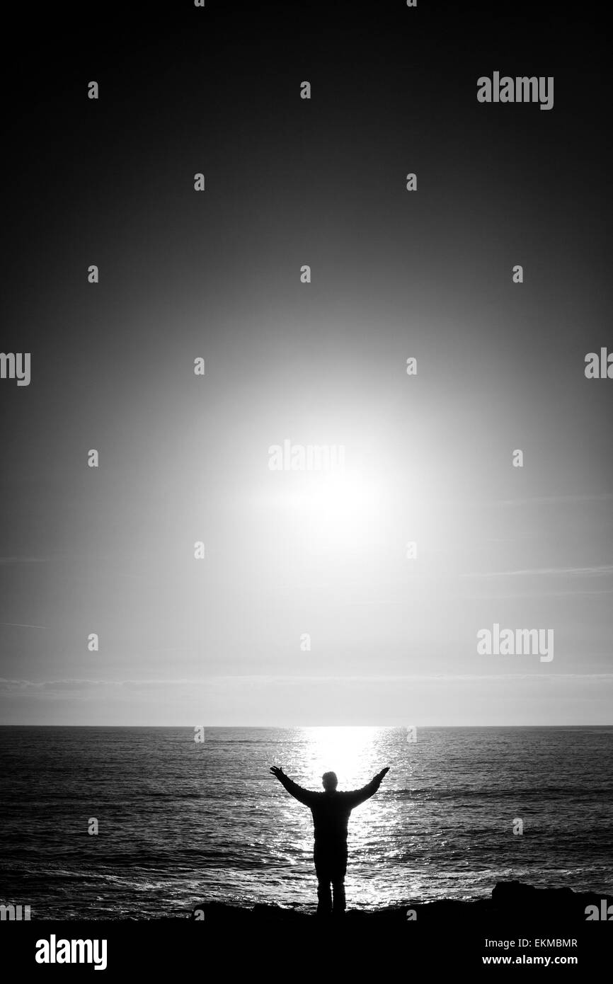 Silhouette of a man with arms outstretched in from of the sea Stock ...