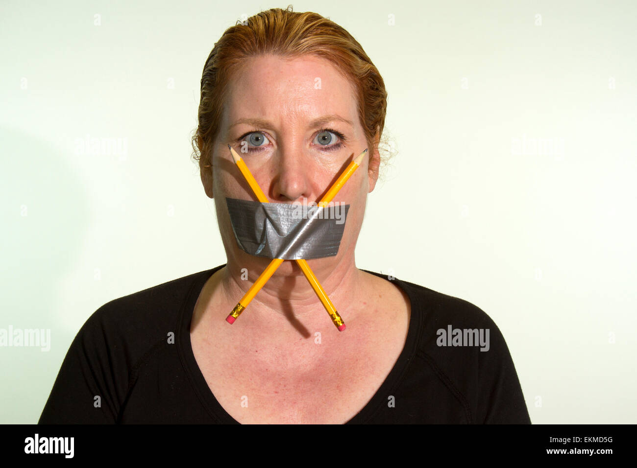 Censorship of Freedom of Speech or Freedom of Press expressed by a woman with duct tape and pencils over her mouth Stock Photo