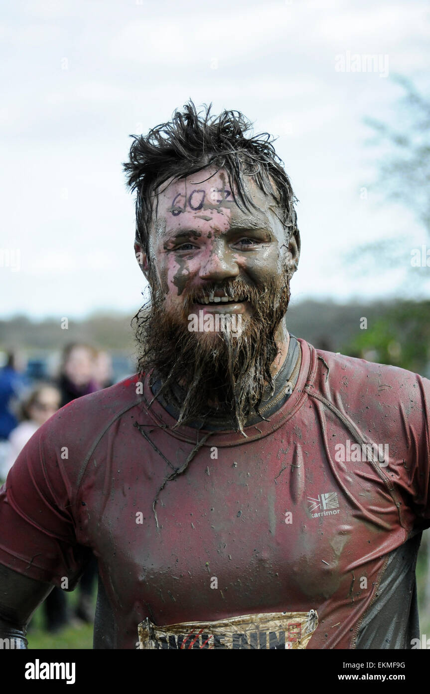 Portrait of mud covered runner at obstacle course race, UK Stock Photo