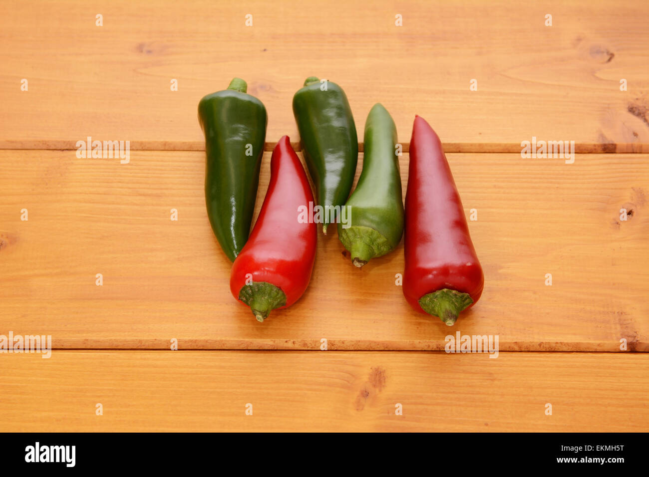 Five red and green hot chillis on a wooden table Stock Photo