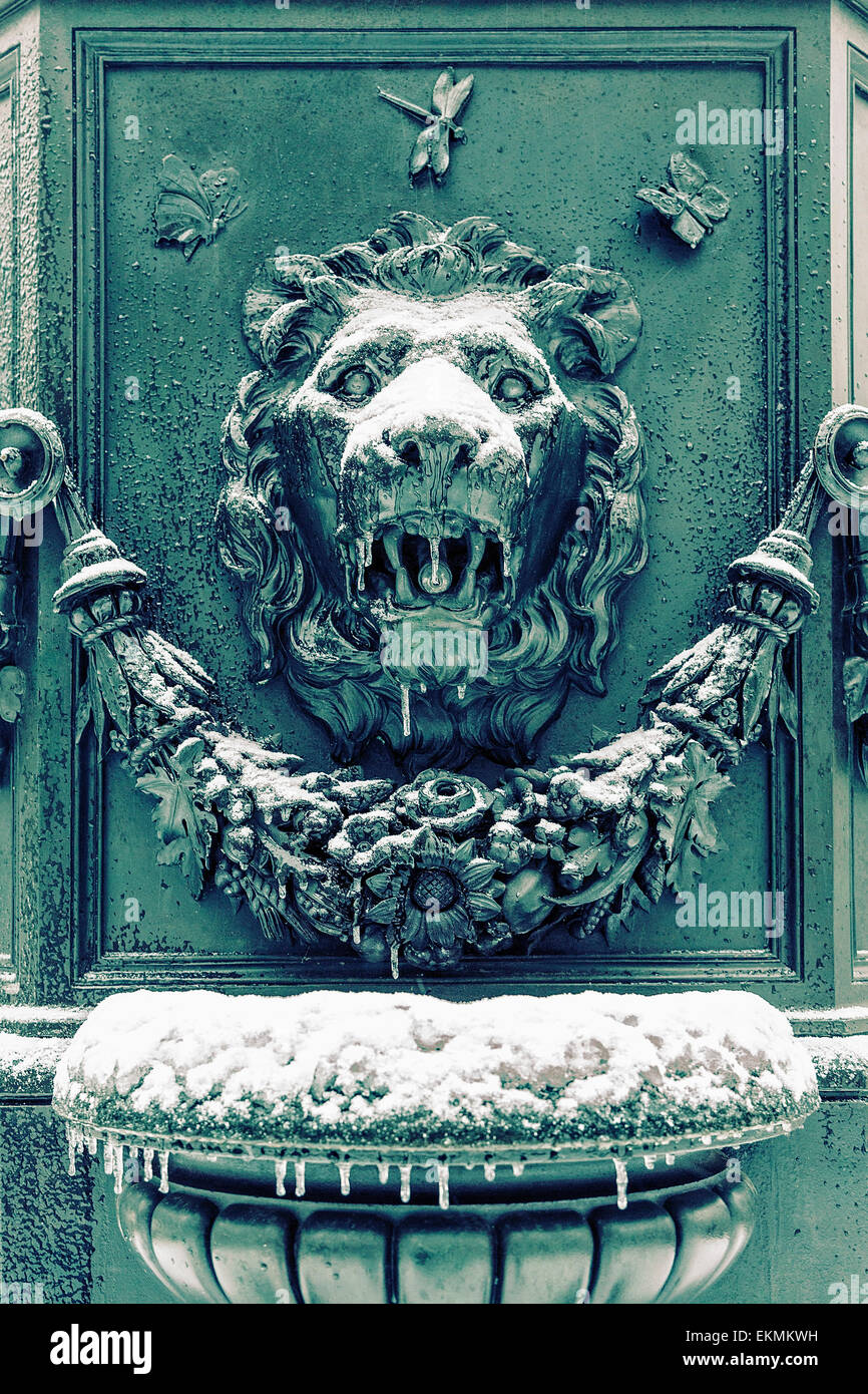 A lion faced fountain in Union Square New York, New York frozen with icicles dripping from it. Stock Photo