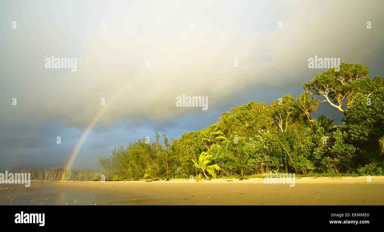 Early morning rainbow on a beach in Queensland - Stock Image