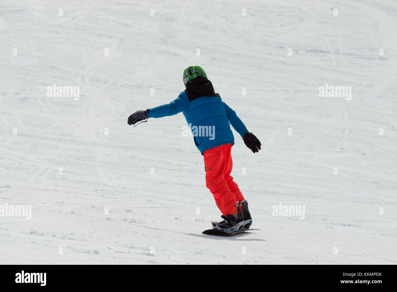 A smooth child snowboarder, is speeding down the alps while turning left to keep the momentum going. Stock Photo