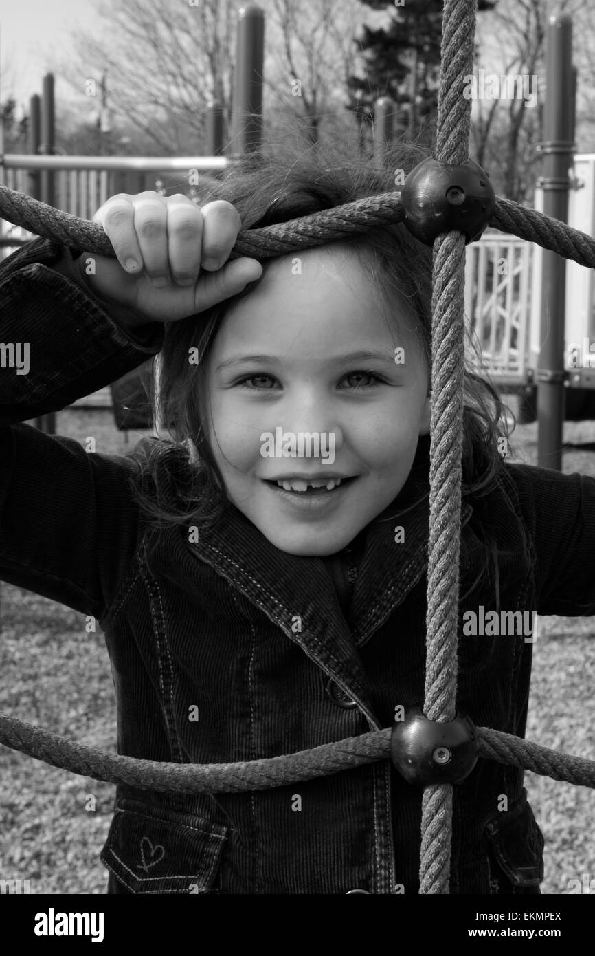 Black and white of a 6 year old girl with a missing front tooth at a playground. Stock Photo