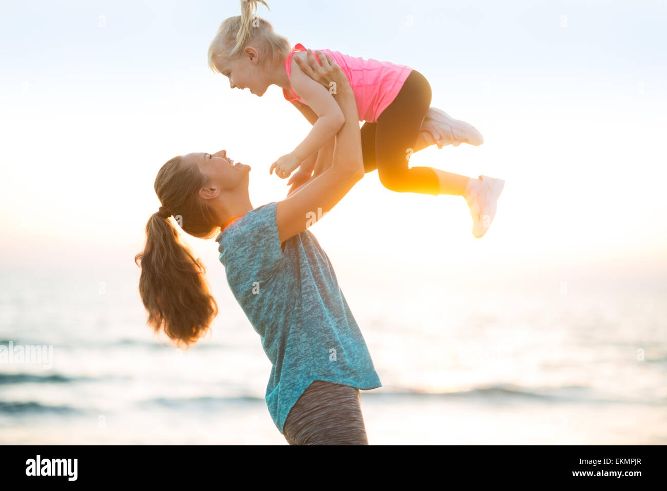 Mother throwing baby up on beach in the evening Stock Photo Alamy