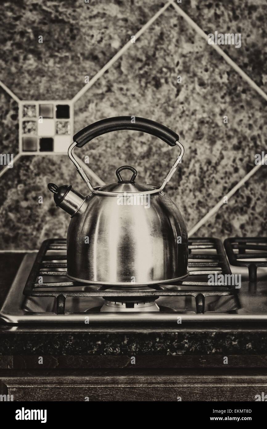 Vintage concept of a stainless steel tea pot on stove top. Stock Photo
