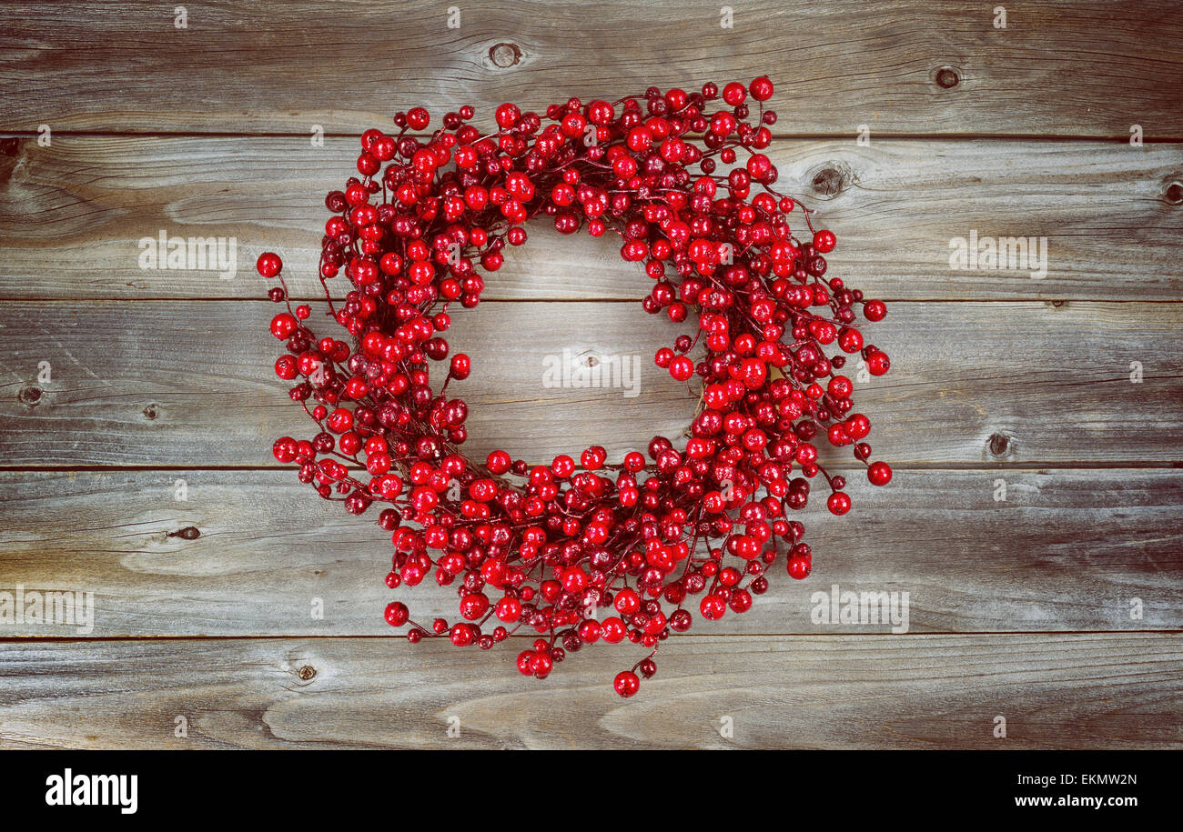 Vintage concept of a red berry holiday wreath on rustic wood Stock Photo
