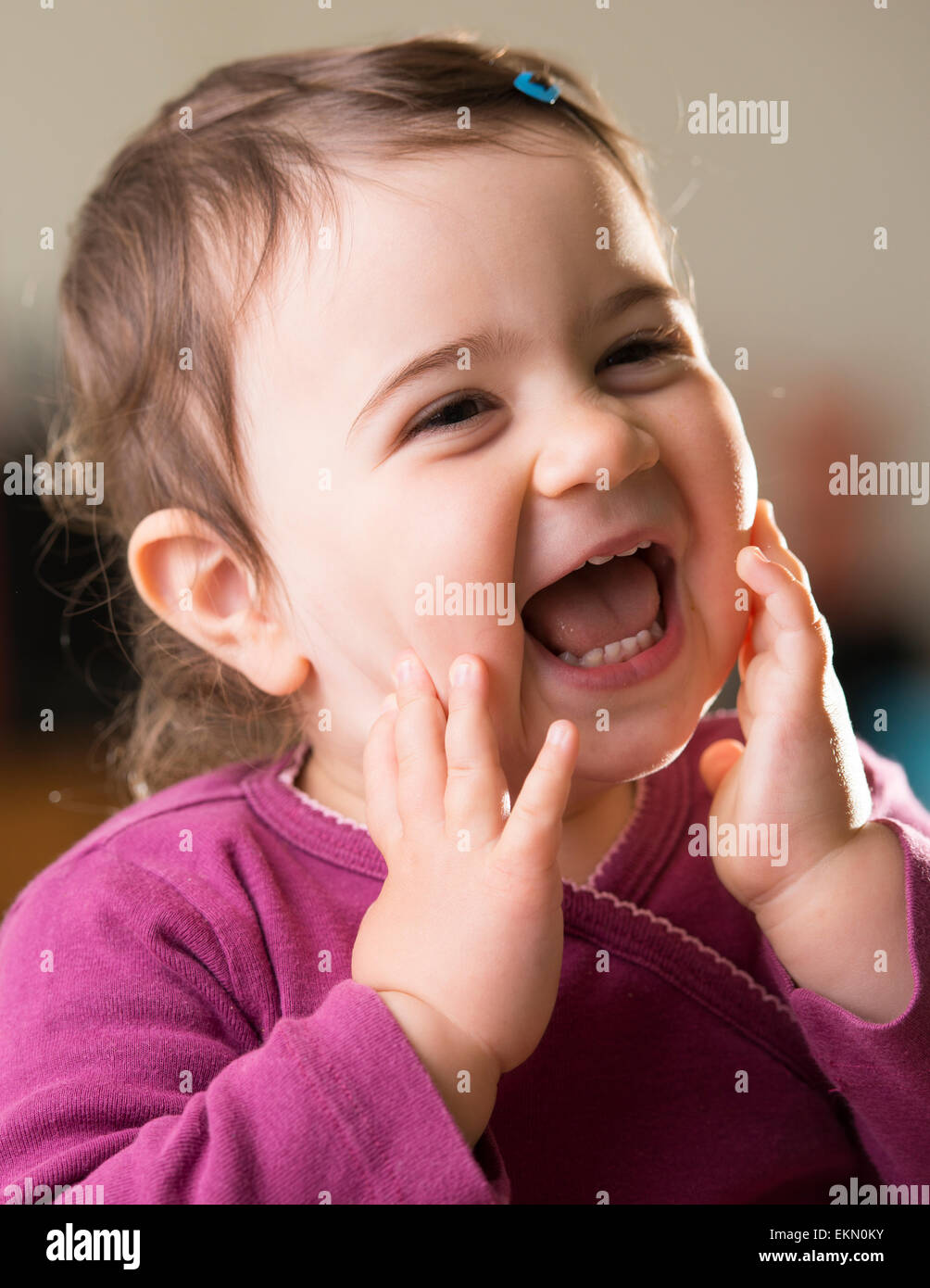 cute baby girl in purple looking aside laughing Stock Photo - Alamy