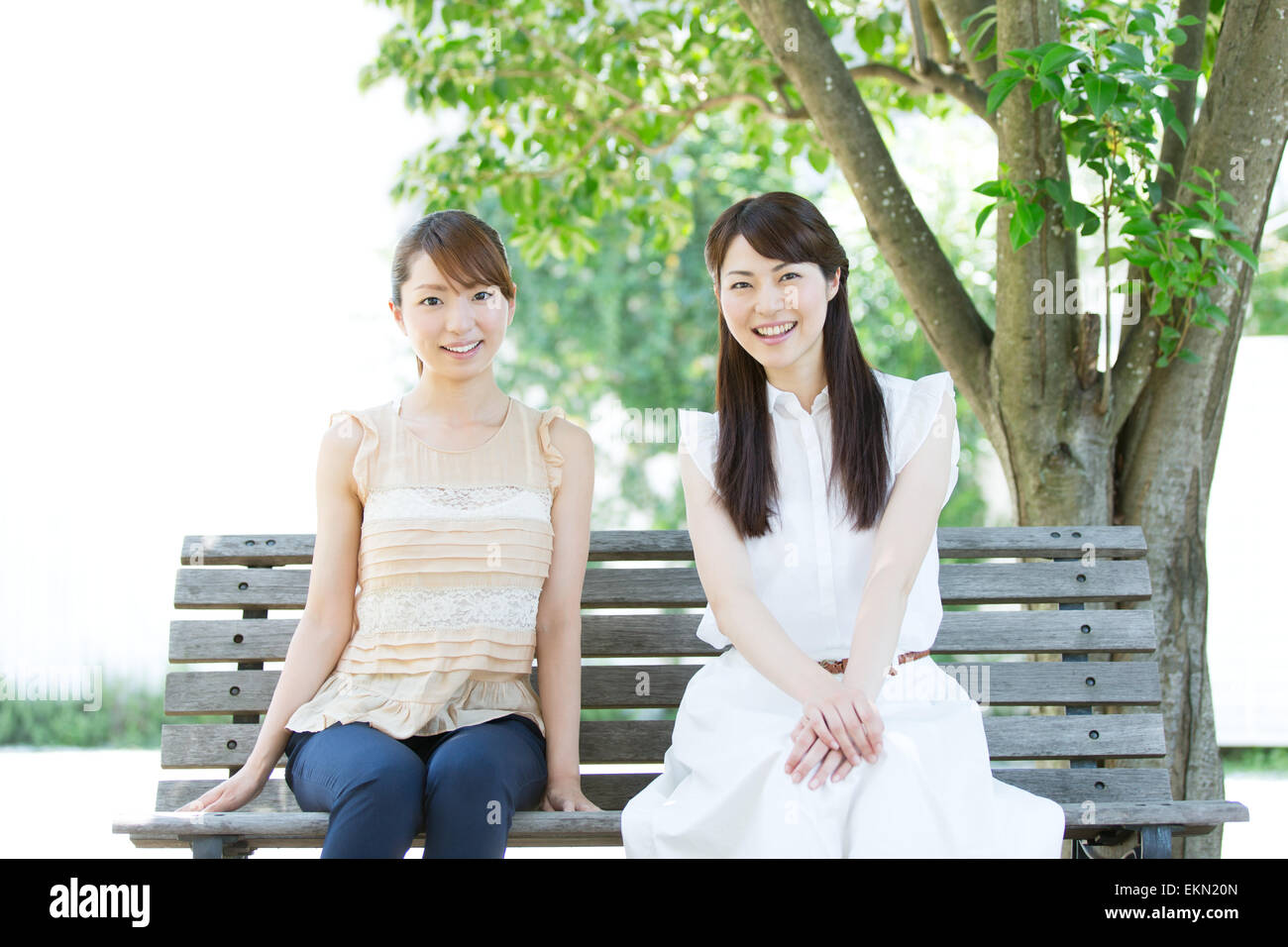 Attractive young girls sitting in a park Stock Photo - Alamy
