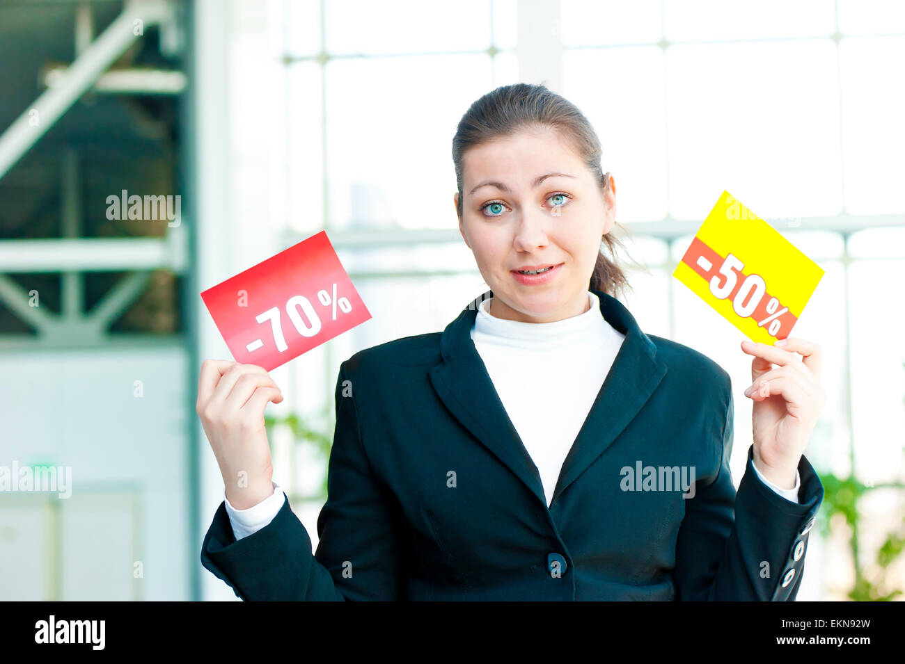 Brunette girl in confusion holds two tablets with discounts Stock Photo